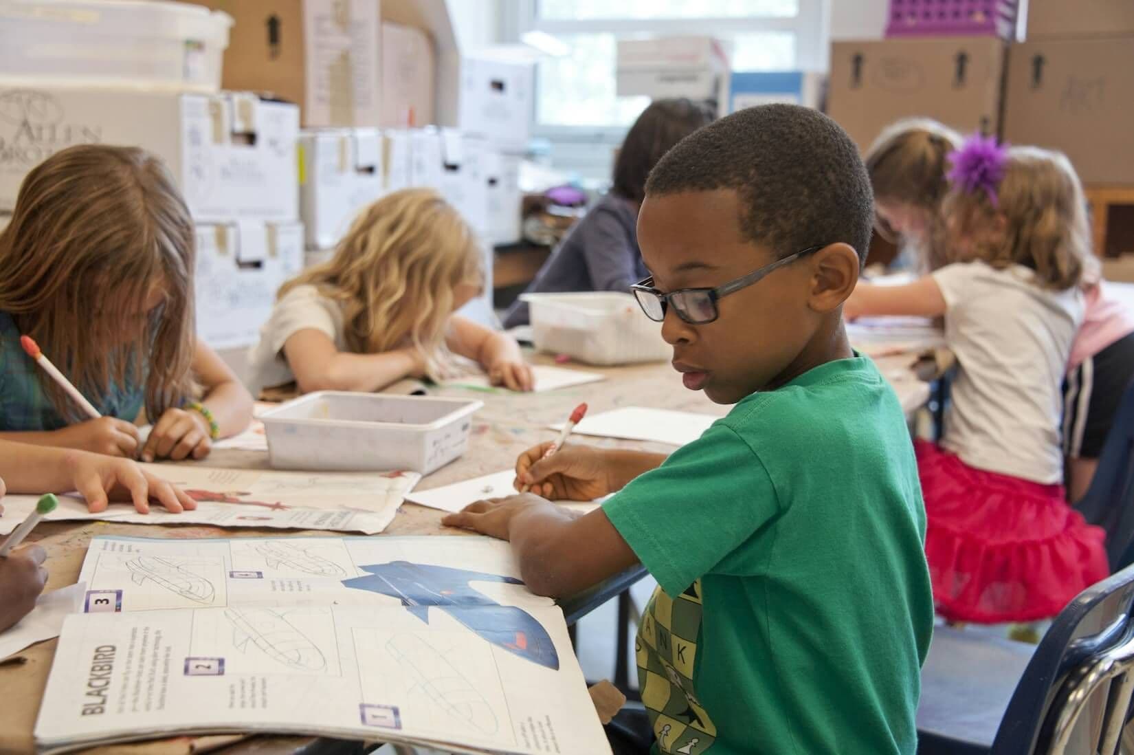 Children writing and working on projects in a classroom setting.